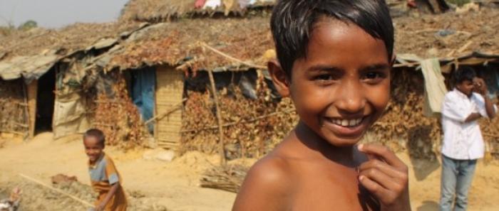 Niño frente a una vivienda de Bangladesh.